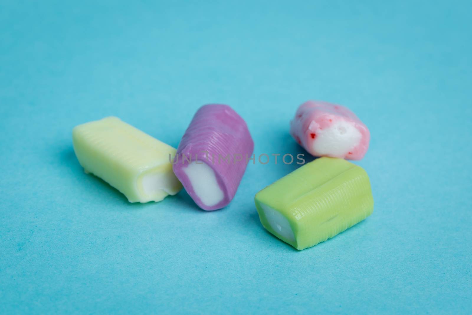 Strawberry, grape, banana and green apple chewy candies on a blue background.
