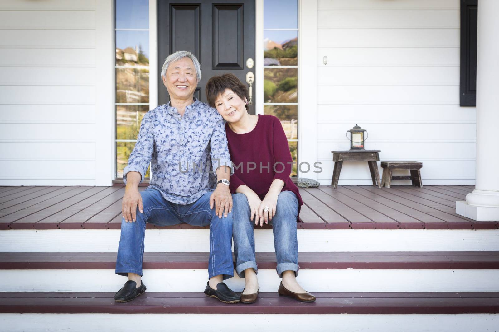 Senior Chinese Couple Sitting on Front Steps of Their House by Feverpitched