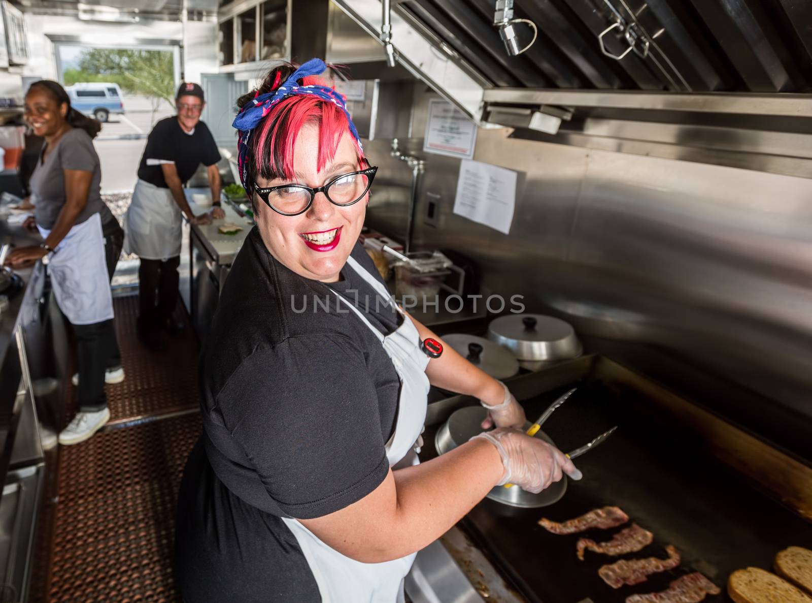 Happy pink haired chef grills bacon on a food truck