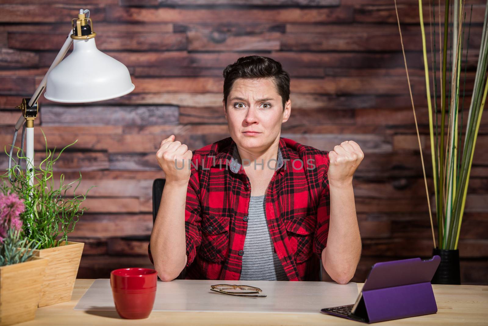 Frustrated woman in flannel shirt with clenched fists