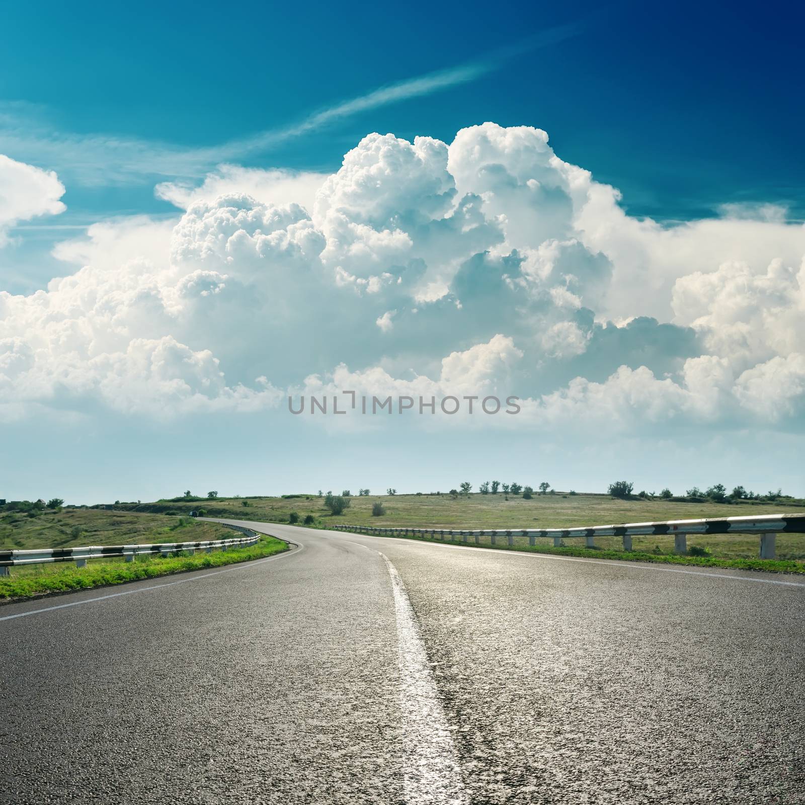 asphalt road to horizon and clouds over it by mycola