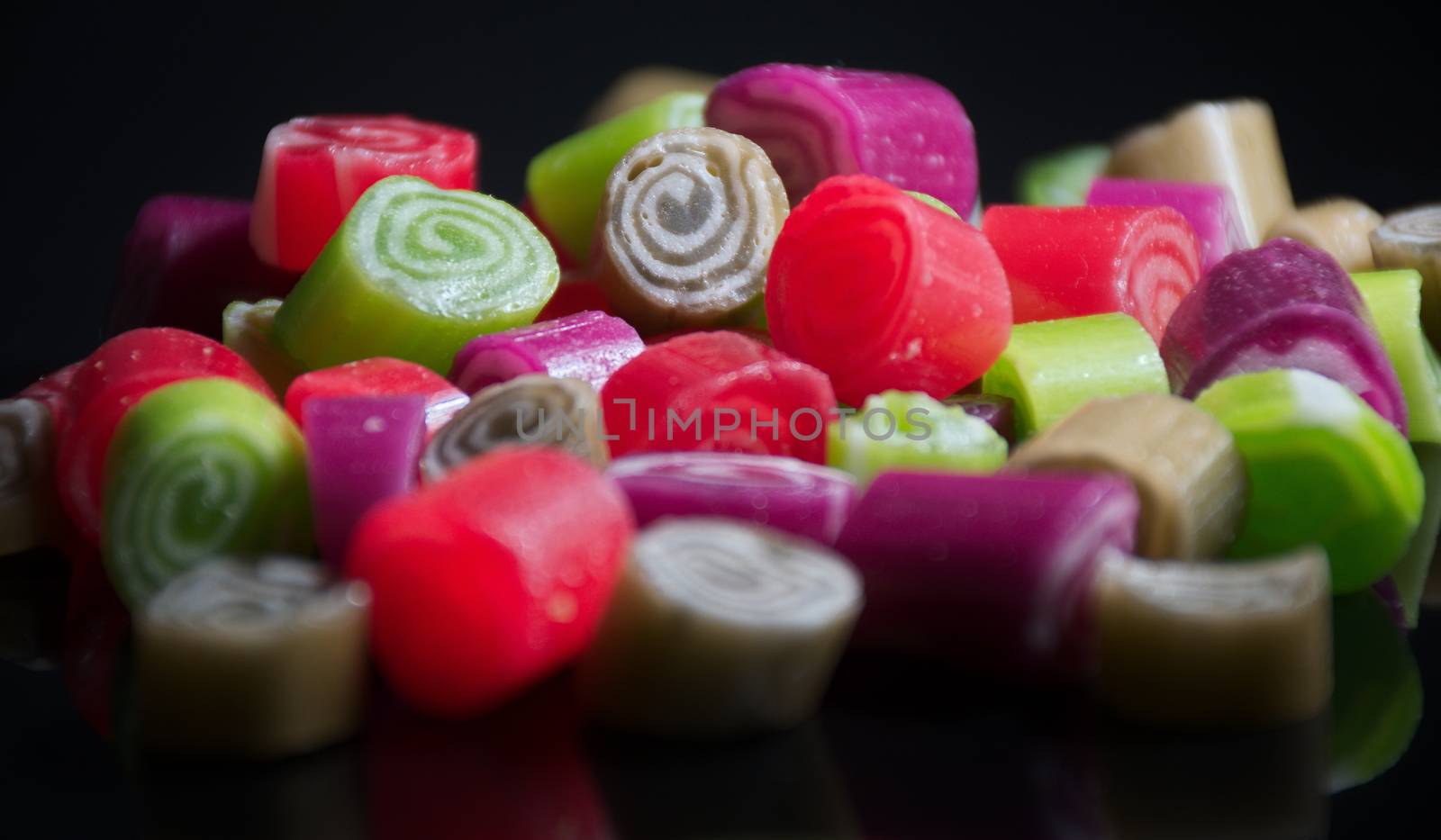 Colorful candies on black background by anderm