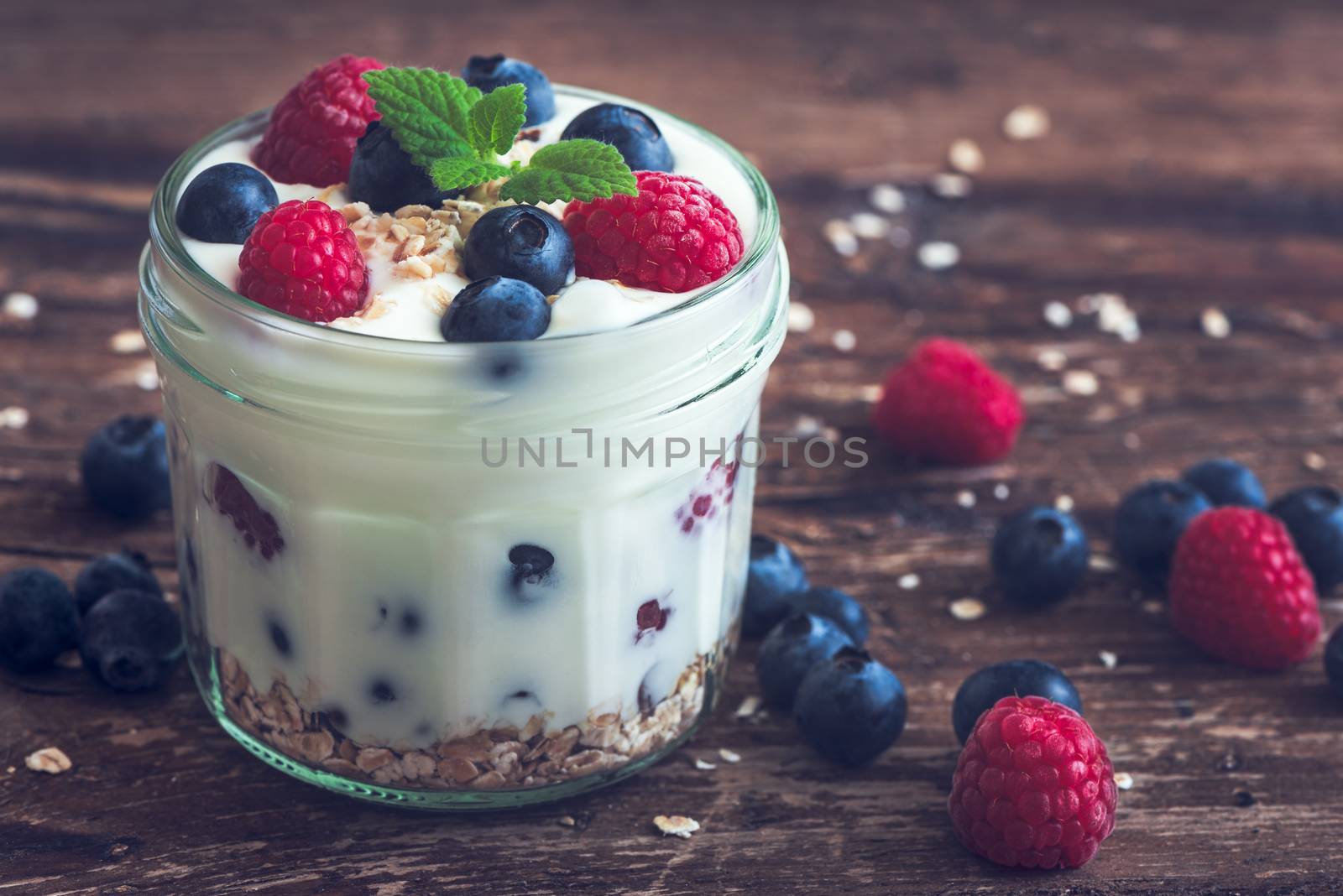 Serving of Yogurt with Whole Fresh Blueberries, Raspberries and Oatmeal on Old Rustic Wooden Table