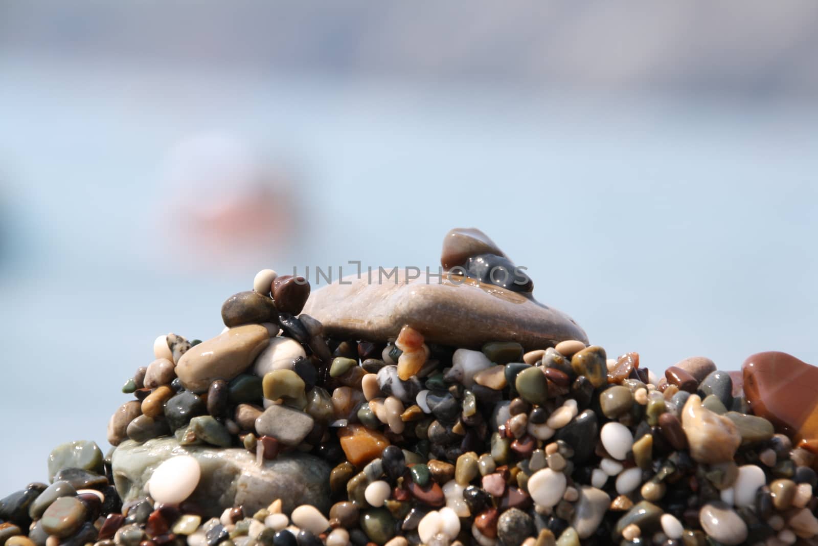 Beach with colorful and round pebbles and blue sky