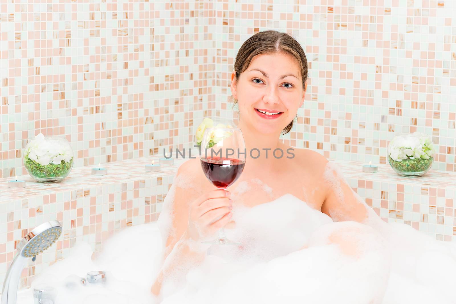 romantic girl with a glass of wine in the jacuzzi with foam