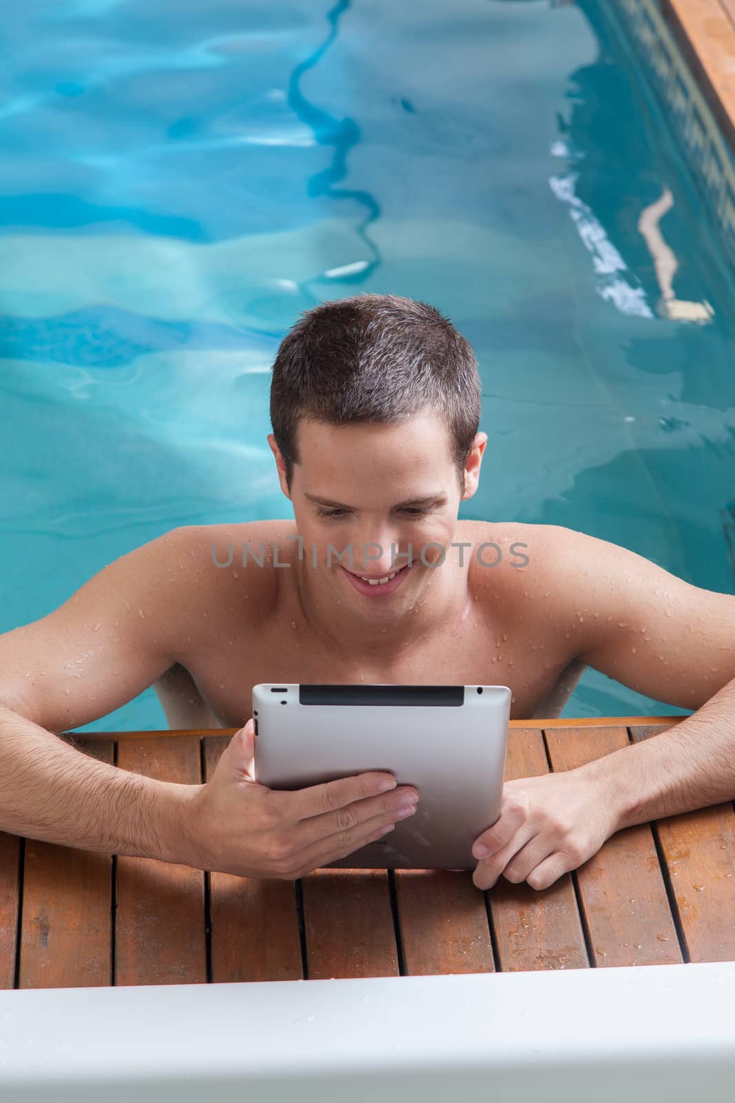 Man play with a tablet in the edge of the pool