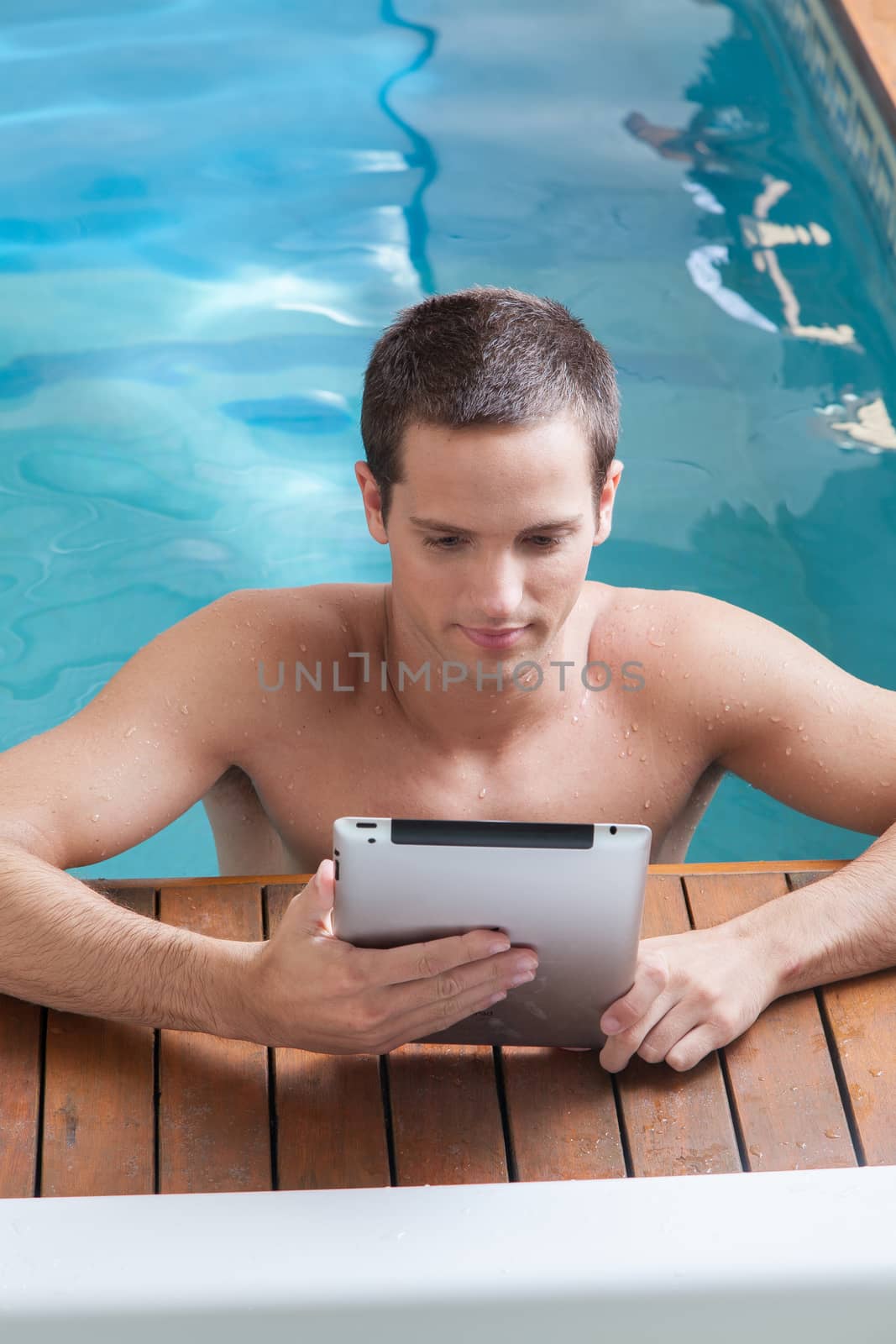 Man play with a tablet in the edge of the pool by ifilms