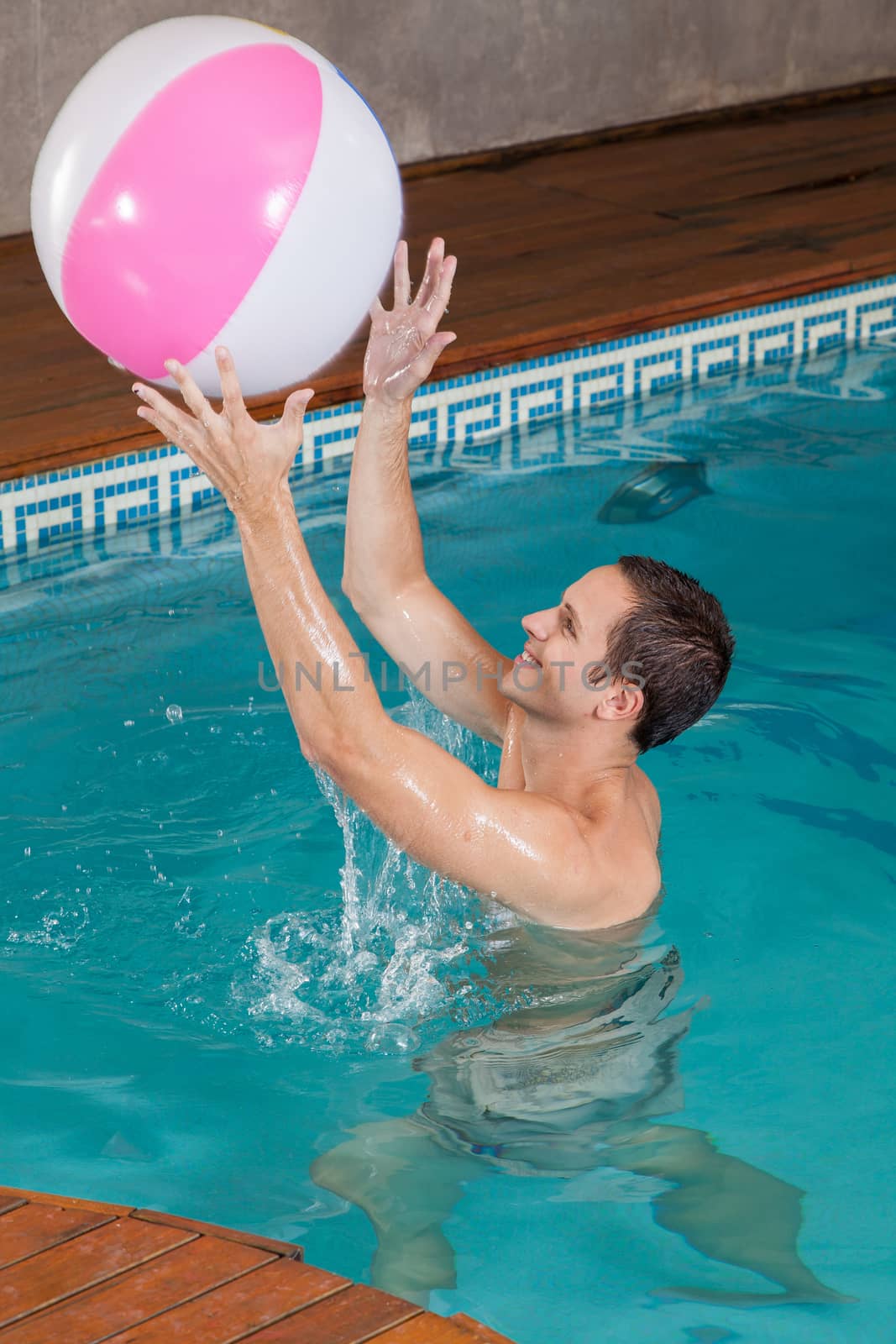 Man playing with inflatable ball inside the pool