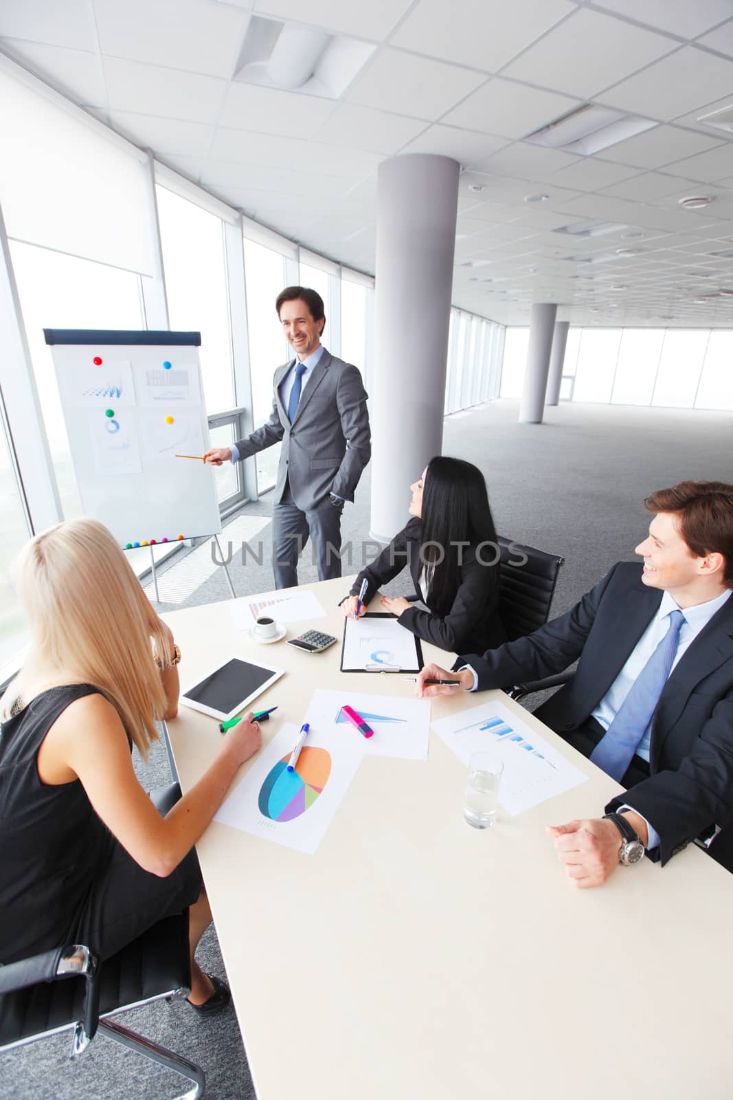 Workers at business meeting looking at presentation of financial reports in modern office