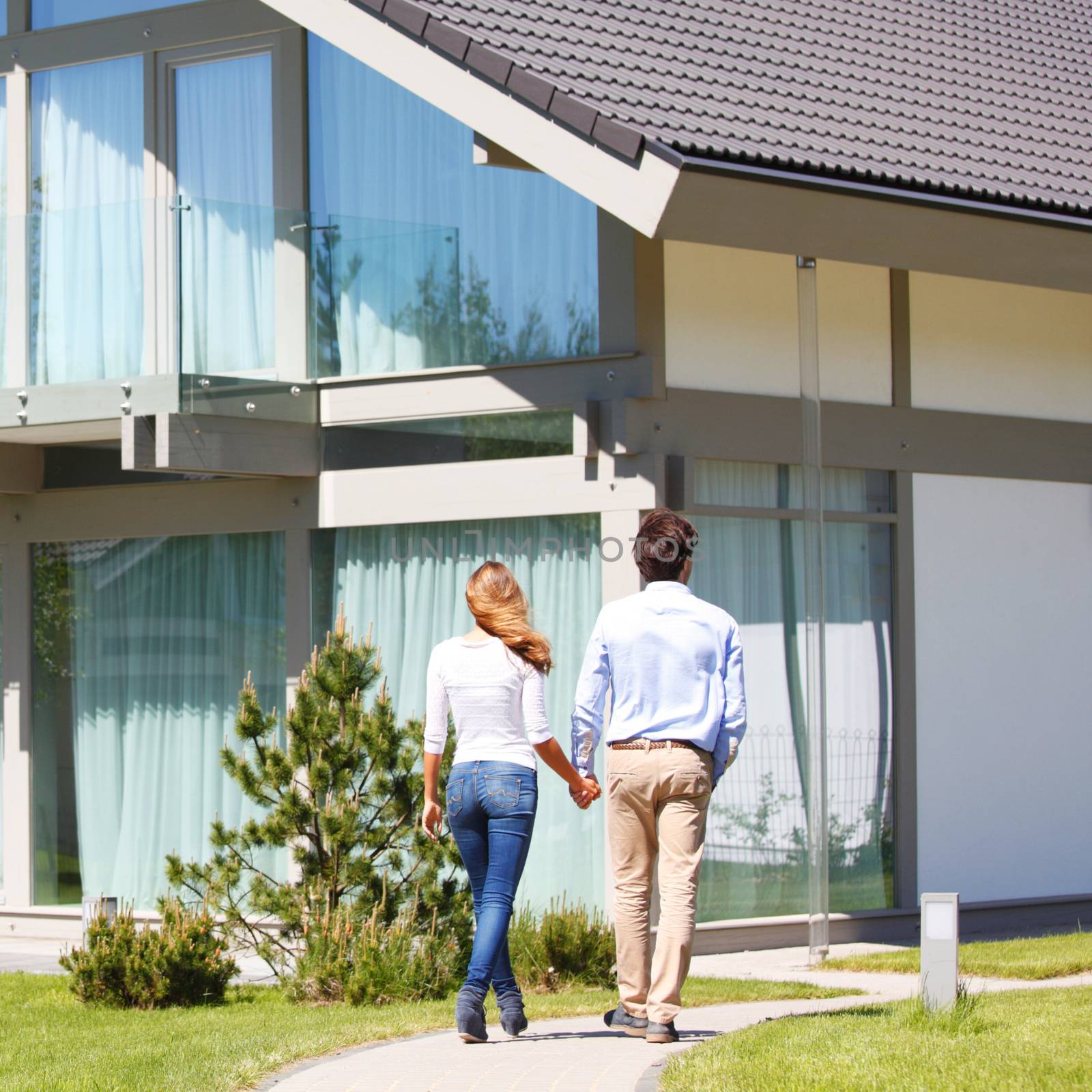 couple walking towards house while holding hands