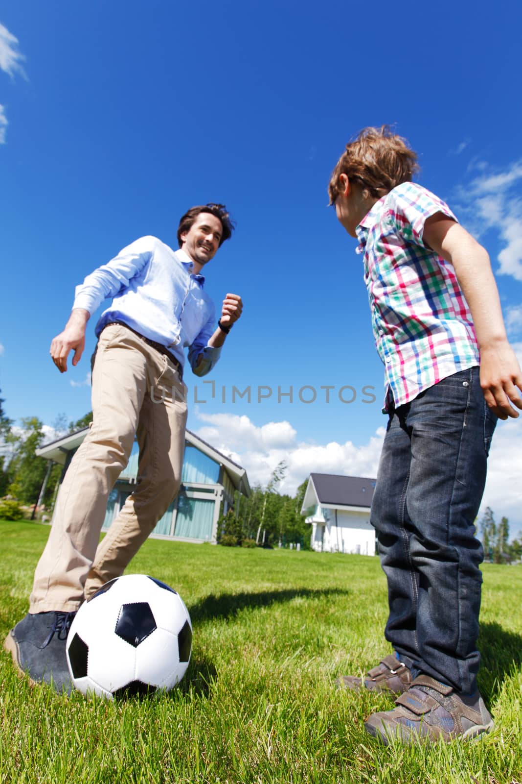 father and son playing football in front of their house