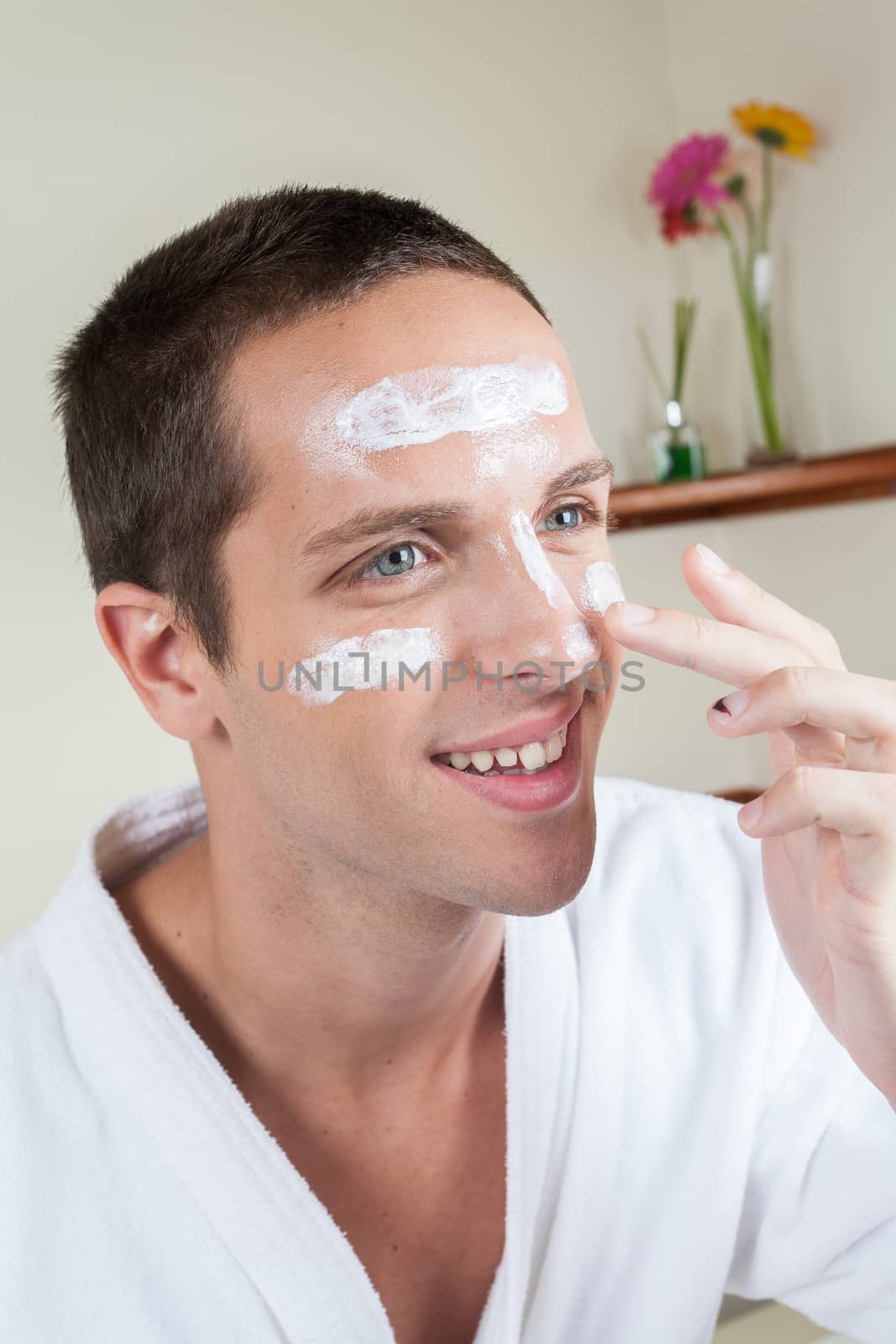 Happy man applying face cream