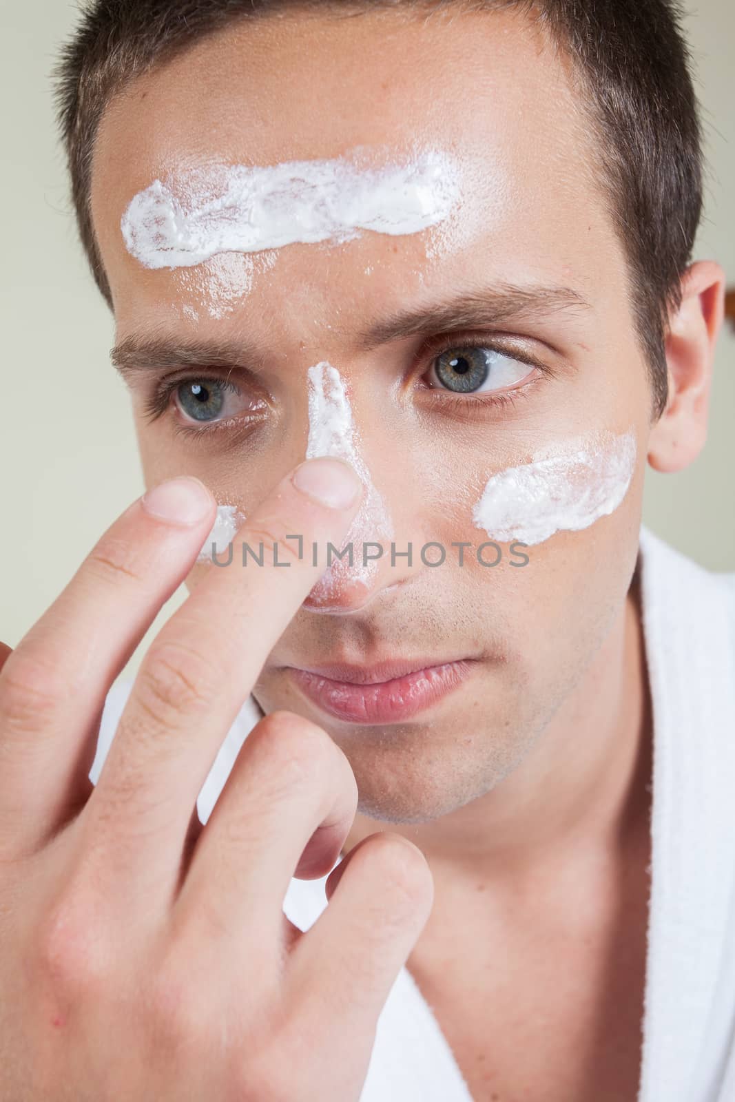 Serious man applying face cream