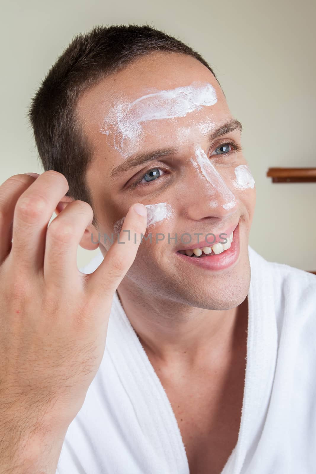 Happy guy putting face cream with your finger
