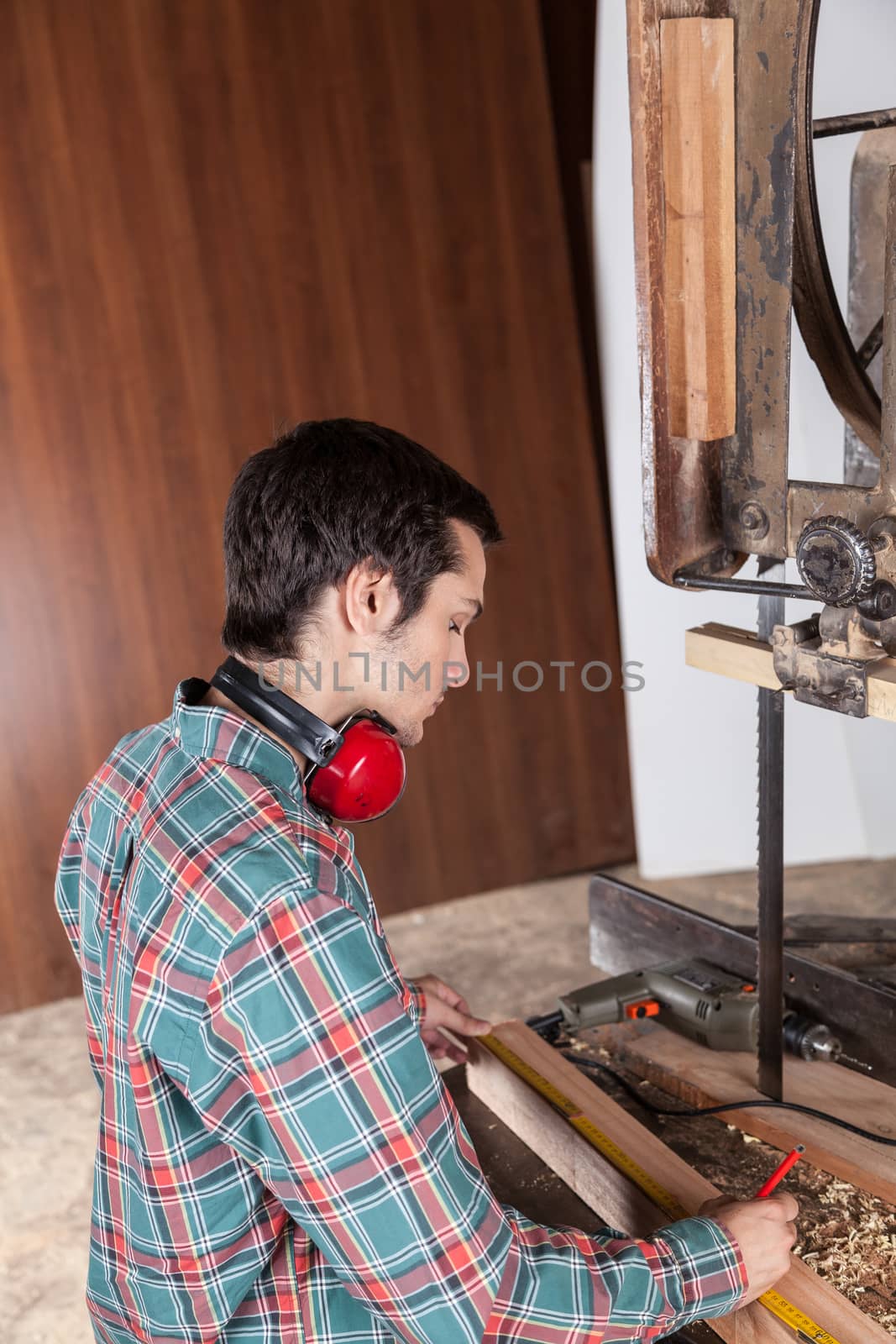 Serious man measuring piece of wood