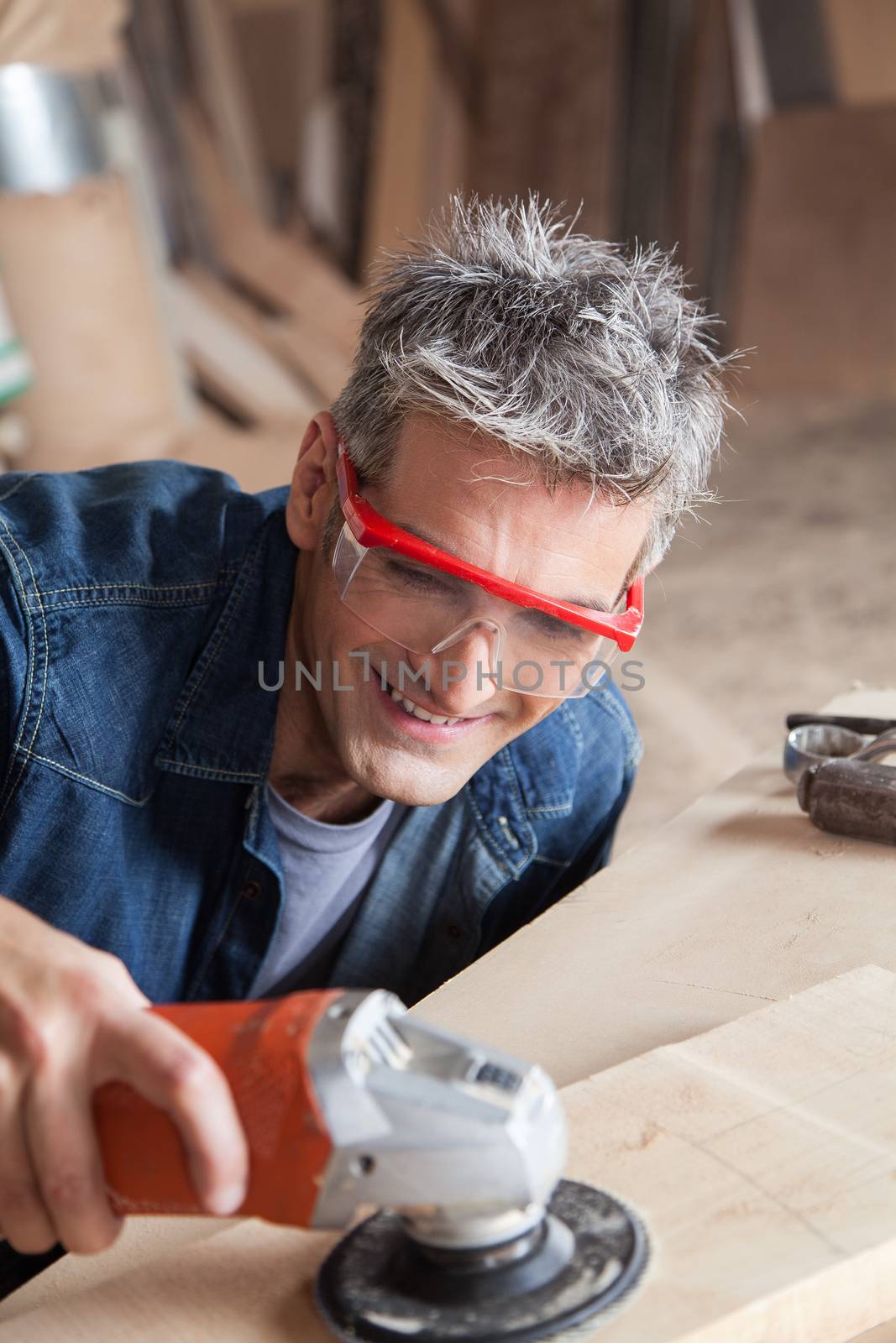 Smiling carpenter with a sander by ifilms