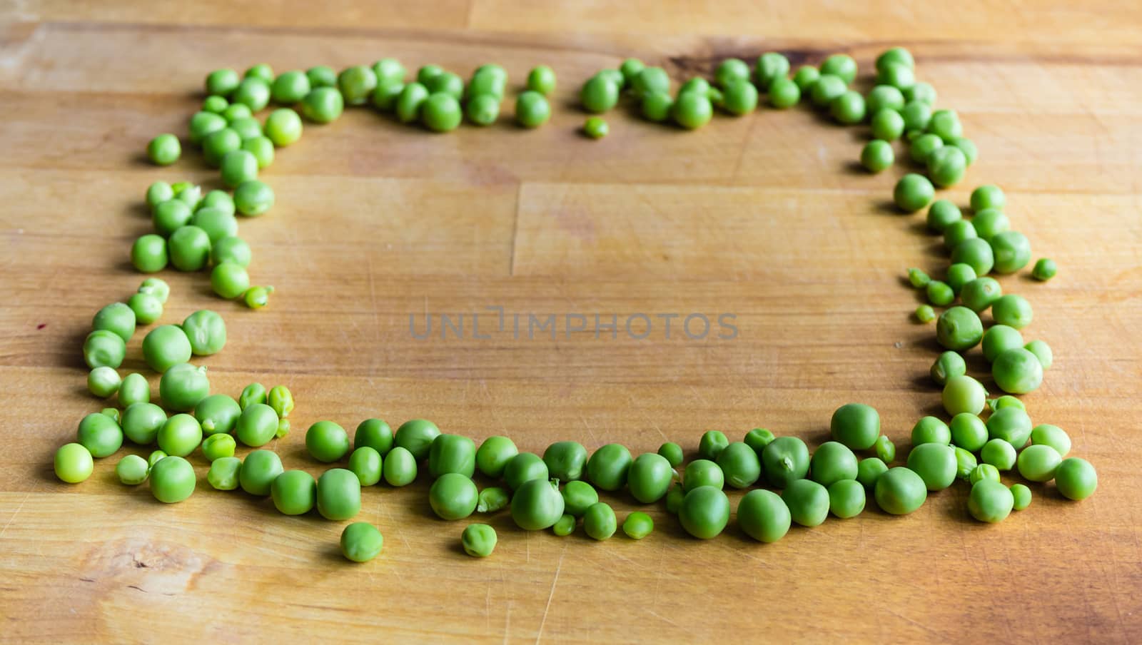 Frame made of peas on wooden board