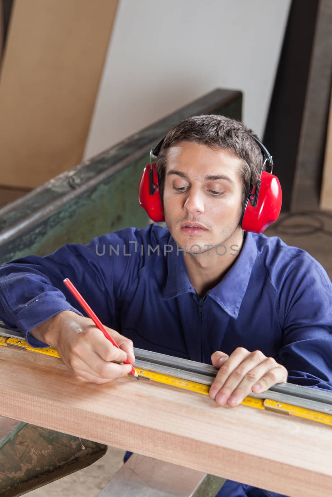 Serious gay measuring a plank in his workshop