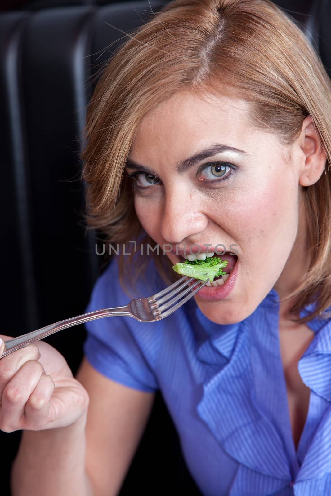 Woman is eating broccoli
