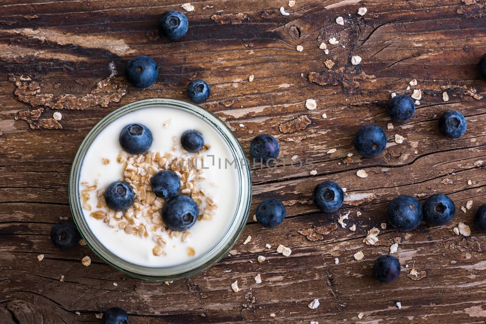 Serving of Yogurt with Whole Fresh Blueberries and Oatmeal on Old Rustic Wooden Table