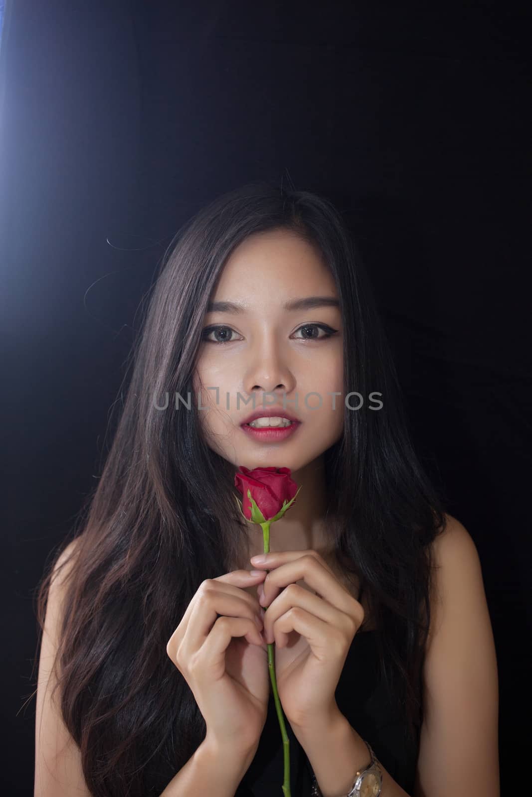 Beautiful asian women and red rose on black background .