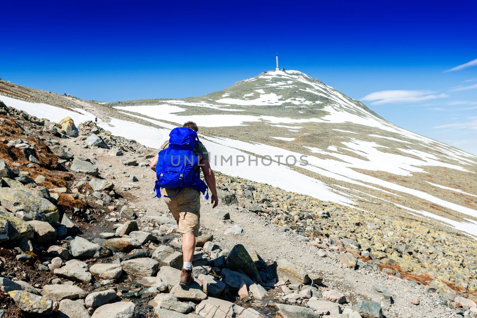 Hiker with big traveling rucksack looking forward on the mountain trail, adventure travel and discovery