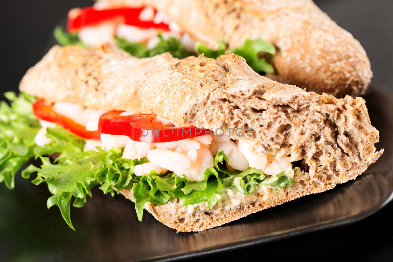 Prawn sandwich on black plate. Studio shot