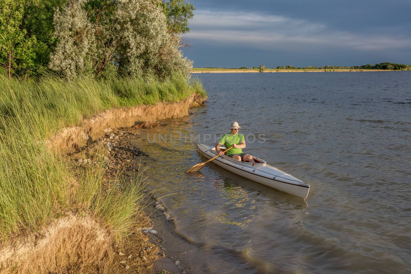 male paddler paddling a decked expedition canoe on a lake in northern Colorado