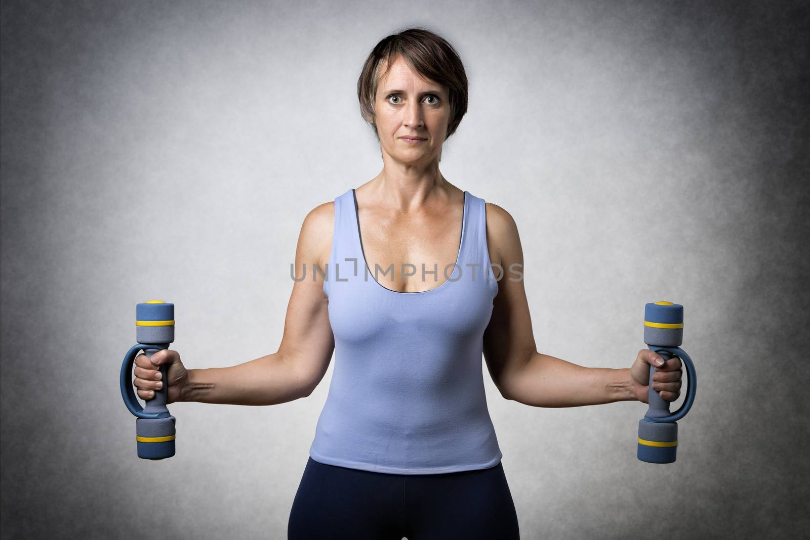 Middle aged handsome woman exercising with dumbbells
