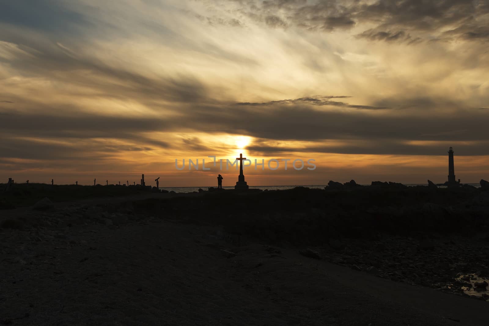 A sunset at a coastline and a light house in the background