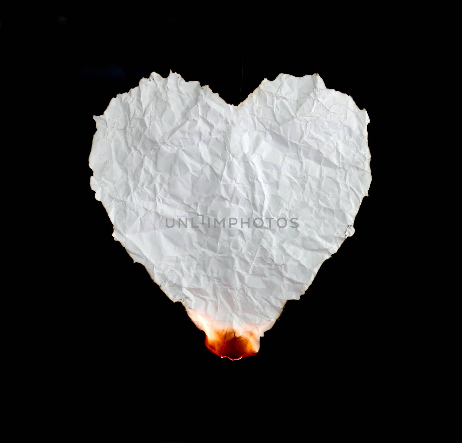 crumpled heart shape paper burning on black background