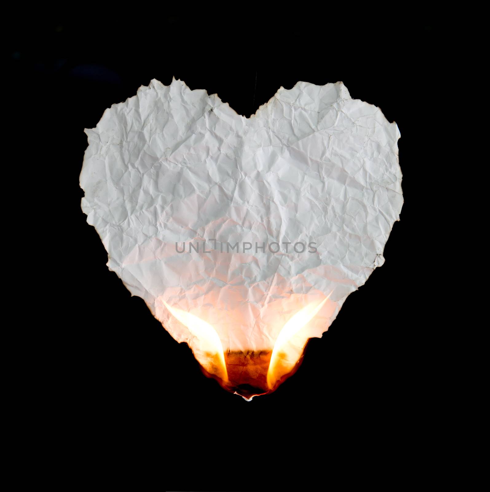 crumpled heart shape paper burning on black background