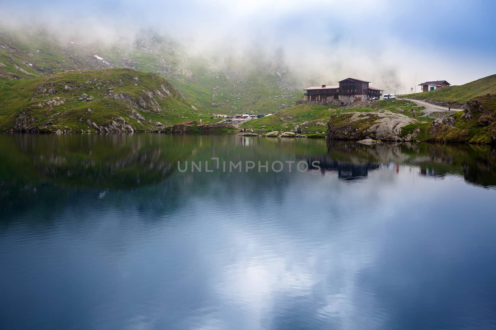 BALEA LAKE, ROMANIA - JUNE 24, 2012: Idyllic view with typical lodge on Balea Lake shore in Fagaras Mountains, Romania.