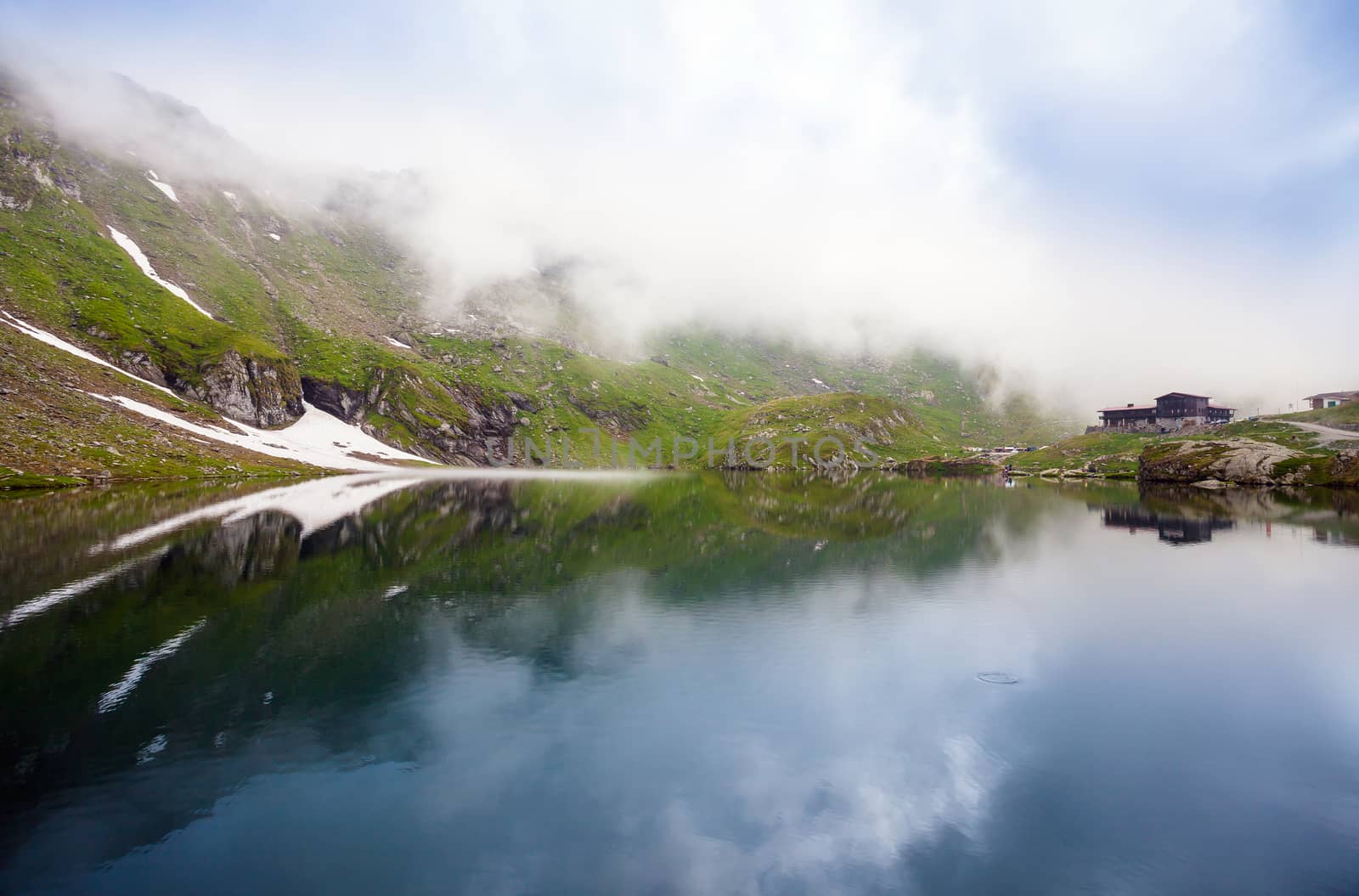 BALEA LAKE, ROMANIA - JUNE 24, 2012: Idyllic view with typical lodge on Balea Lake shore in Fagaras Mountains, Romania.