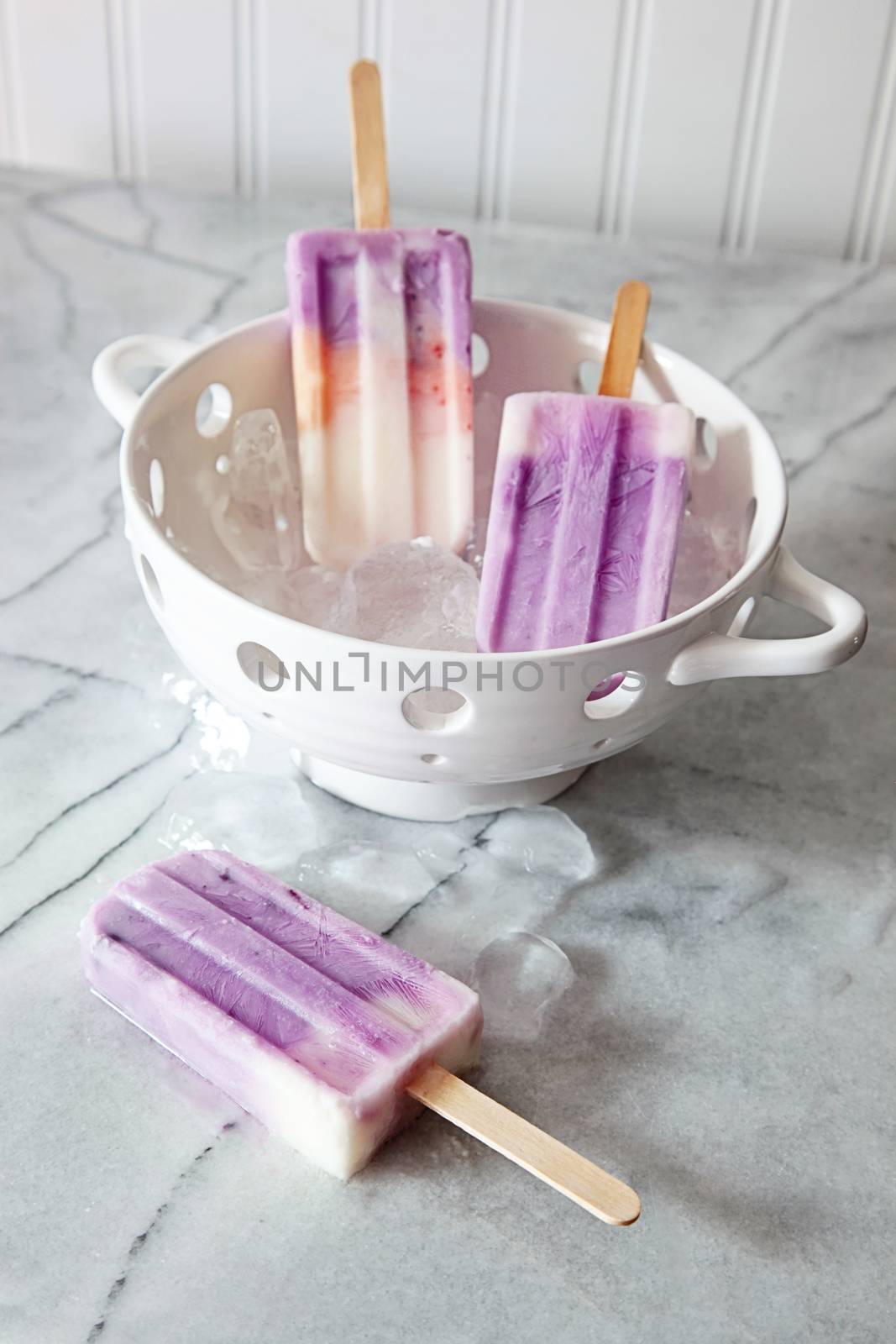 Frozen yogurt popsicles on marble counter by Sandralise