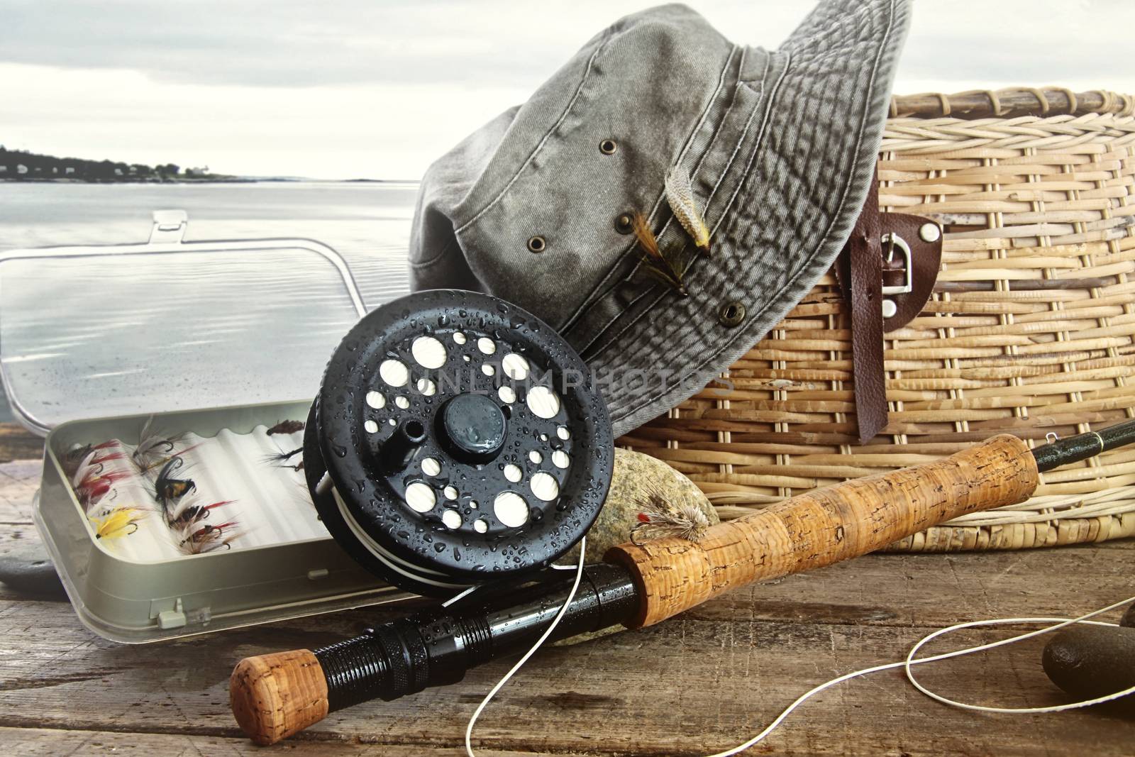 Hat and fly fishing gear on table near the water's edge