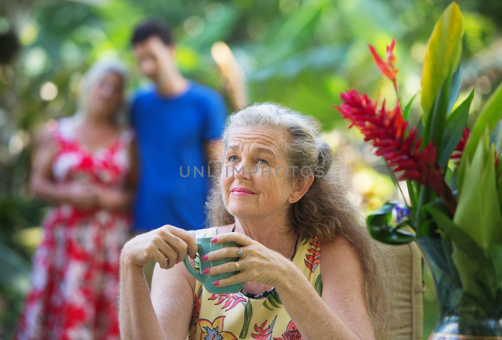 Forgetful older mother with cup near couple