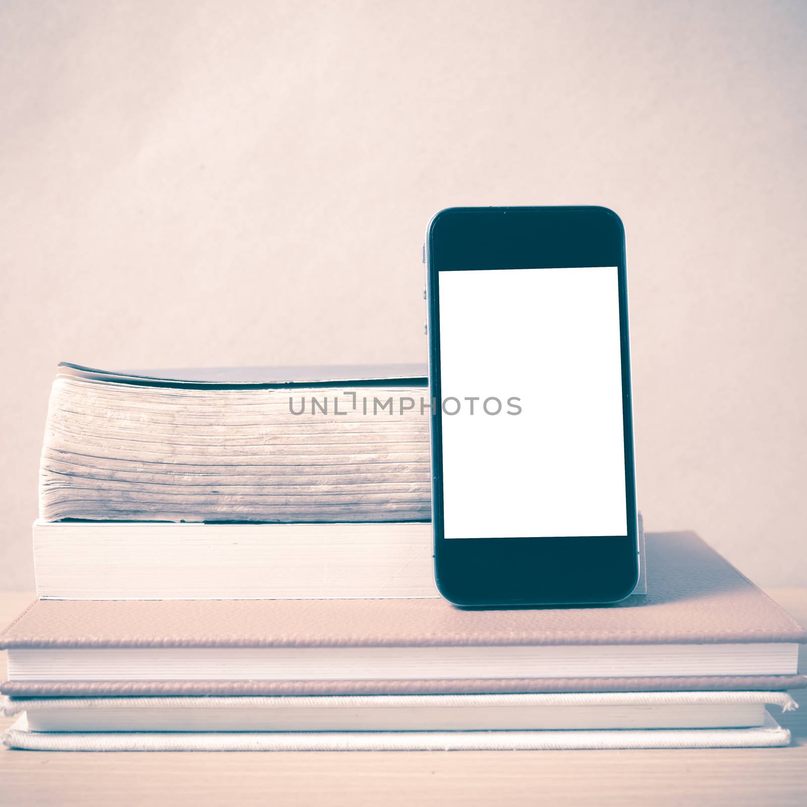 stack of book and smart phone on wood background vintage style