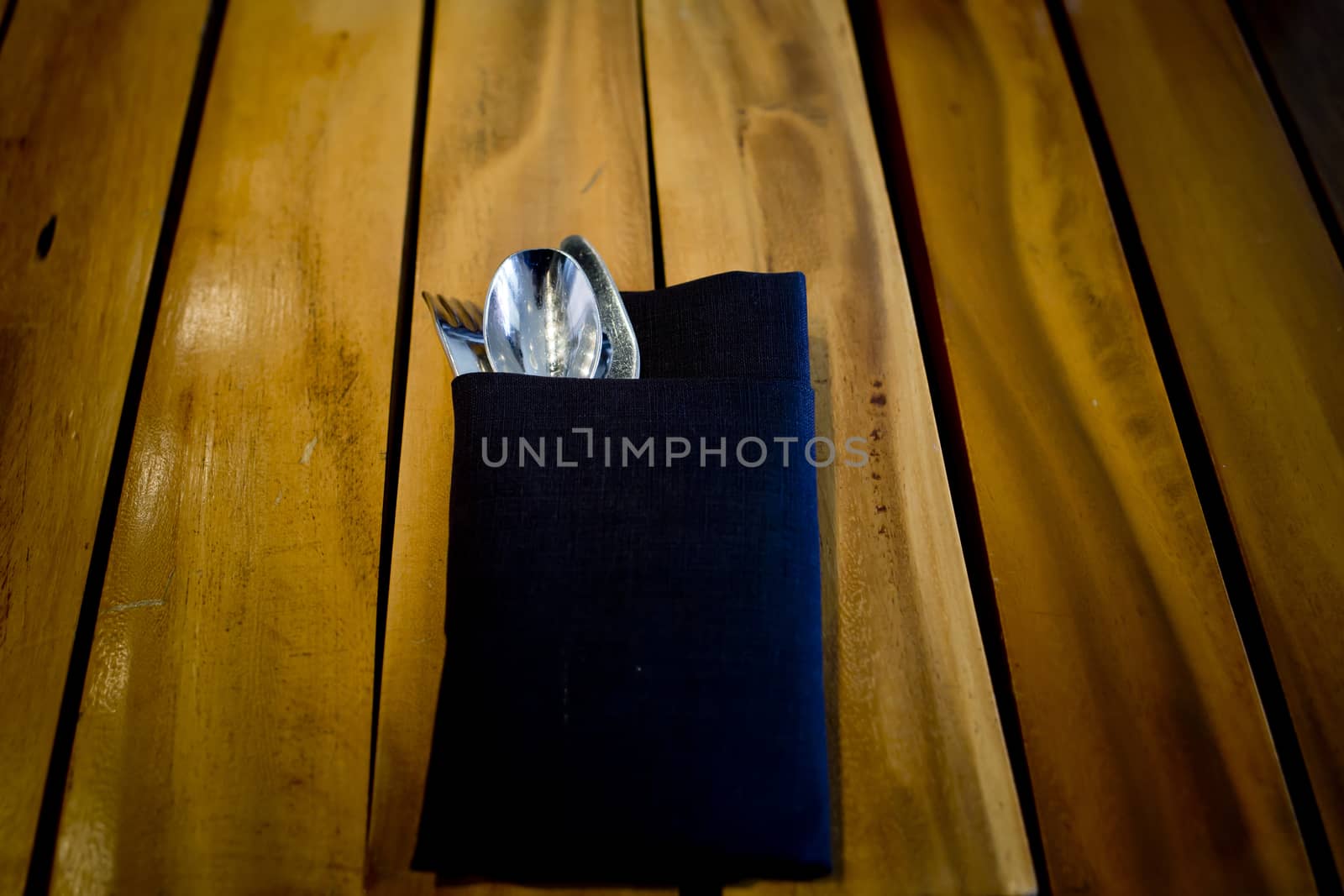 fork and spoon in dark blue cloth,on wooden table background by art9858