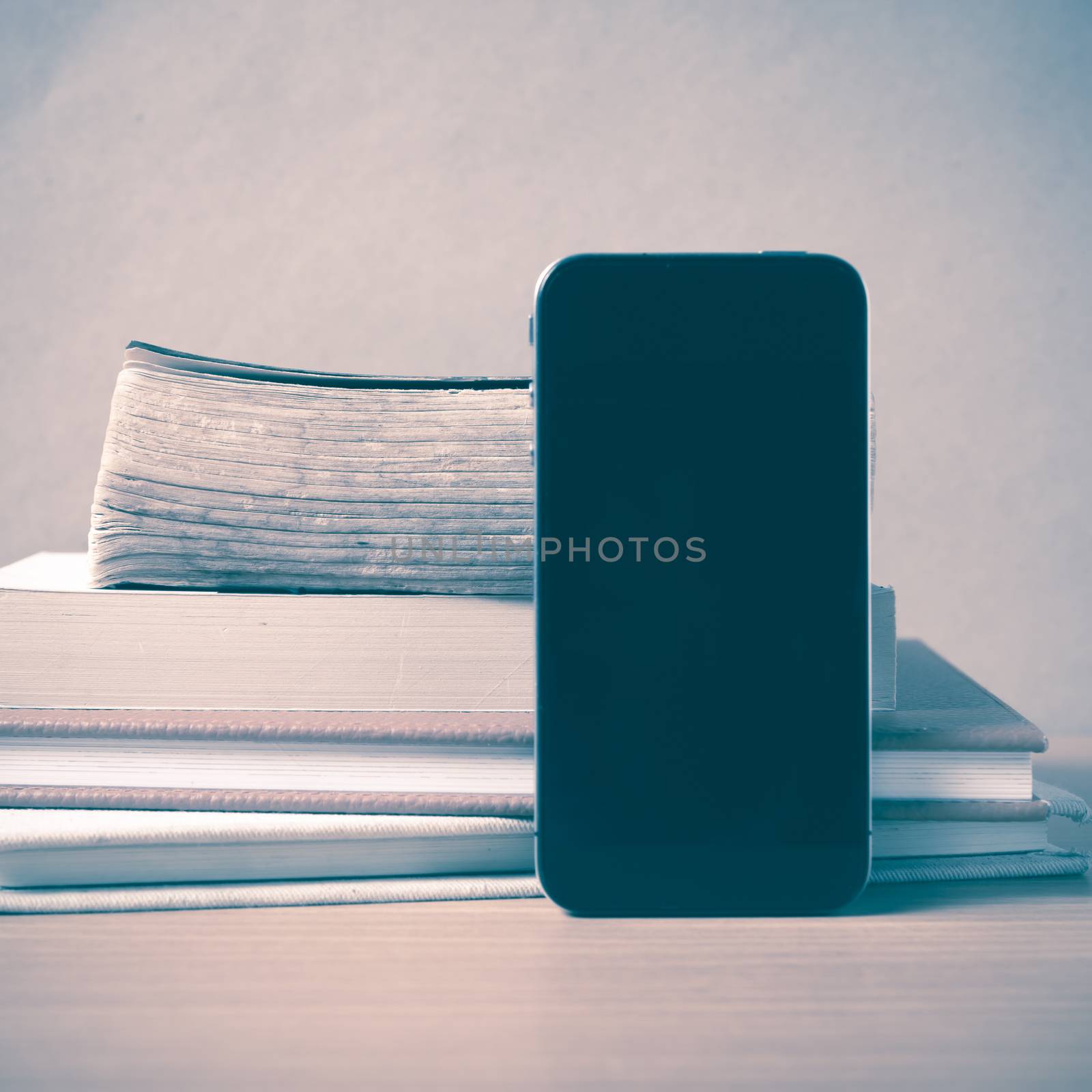 stack of book and smart phone on wood background vintage style