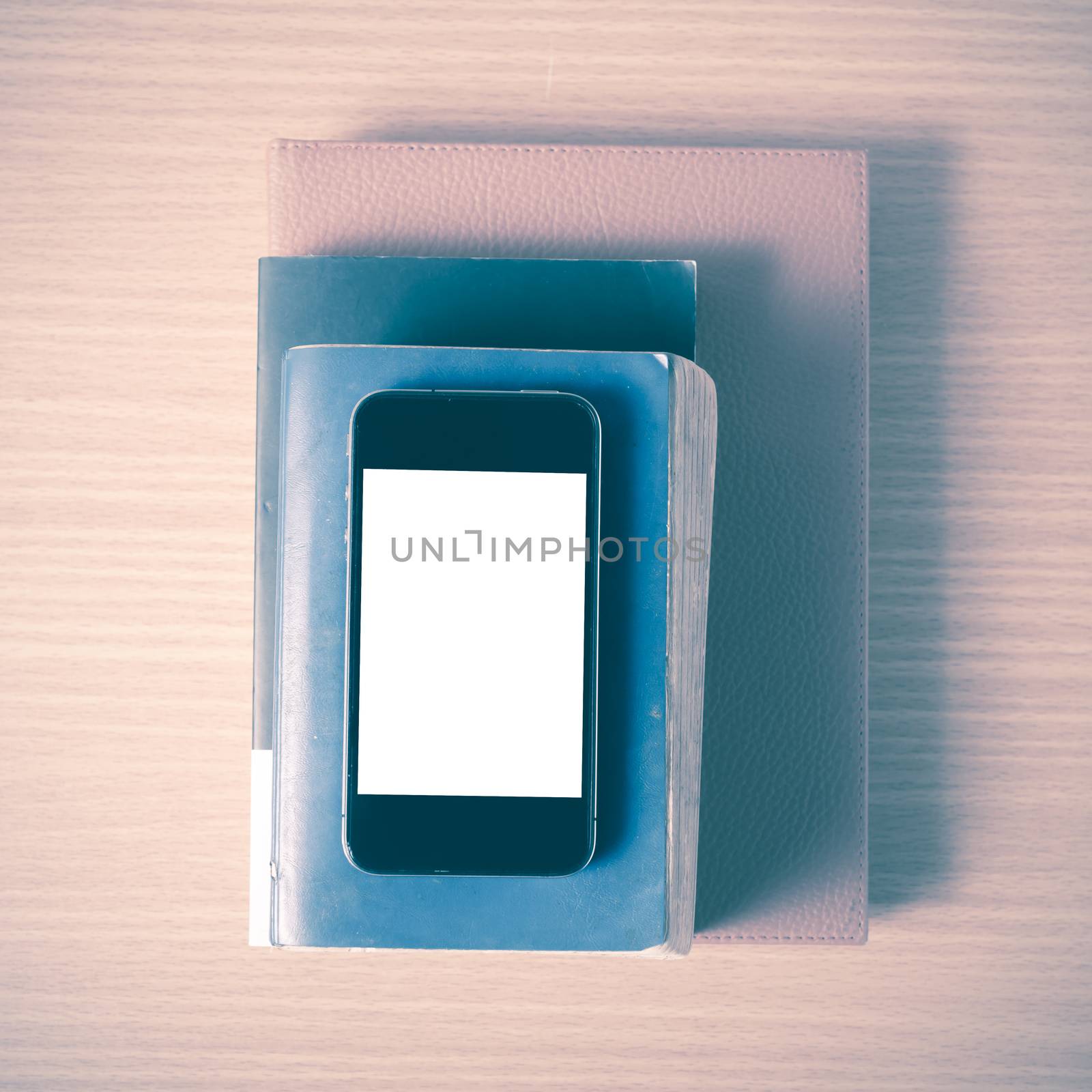 stack of book and smart phone on wood background vintage style