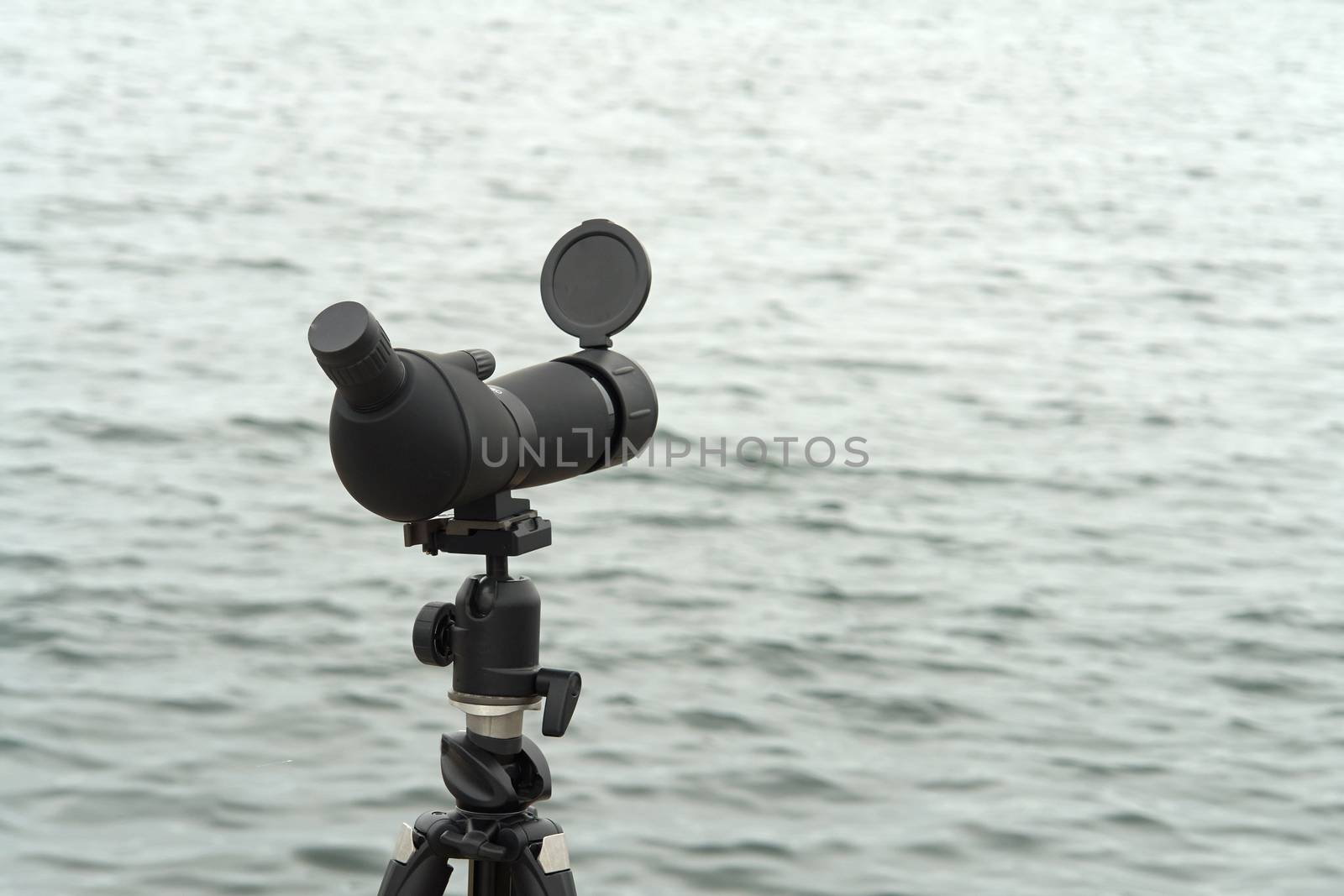 Birdwatching spotting scope monocular on a tripod near the water by Ronyzmbow