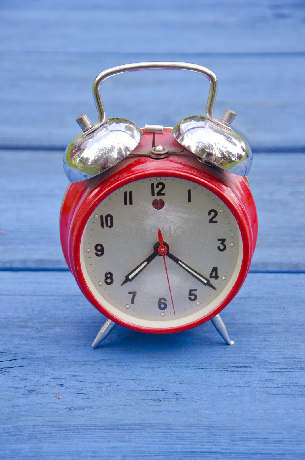 red old style alarm clock on blue wooden garden table