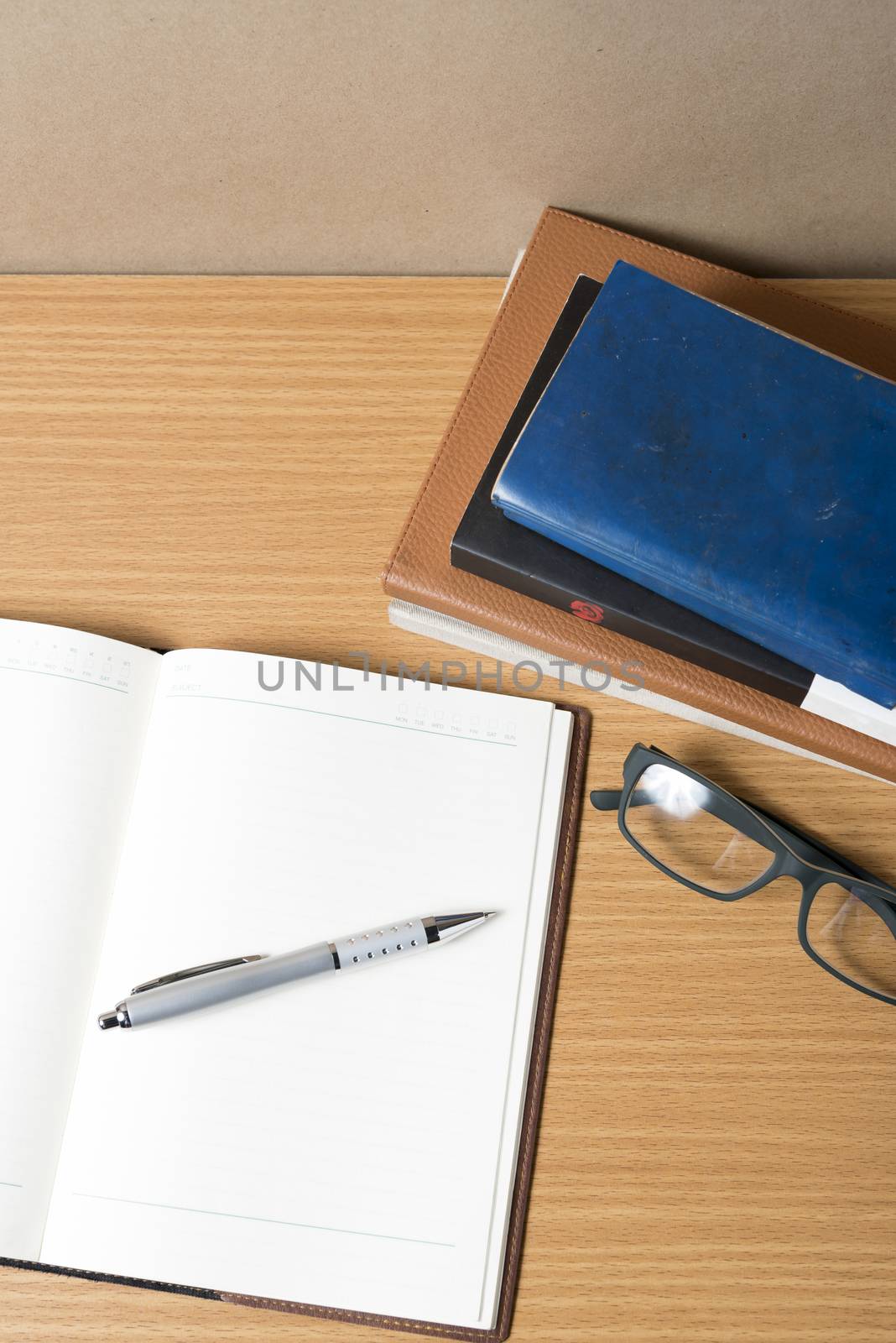 open notebook with stack of book on wood background