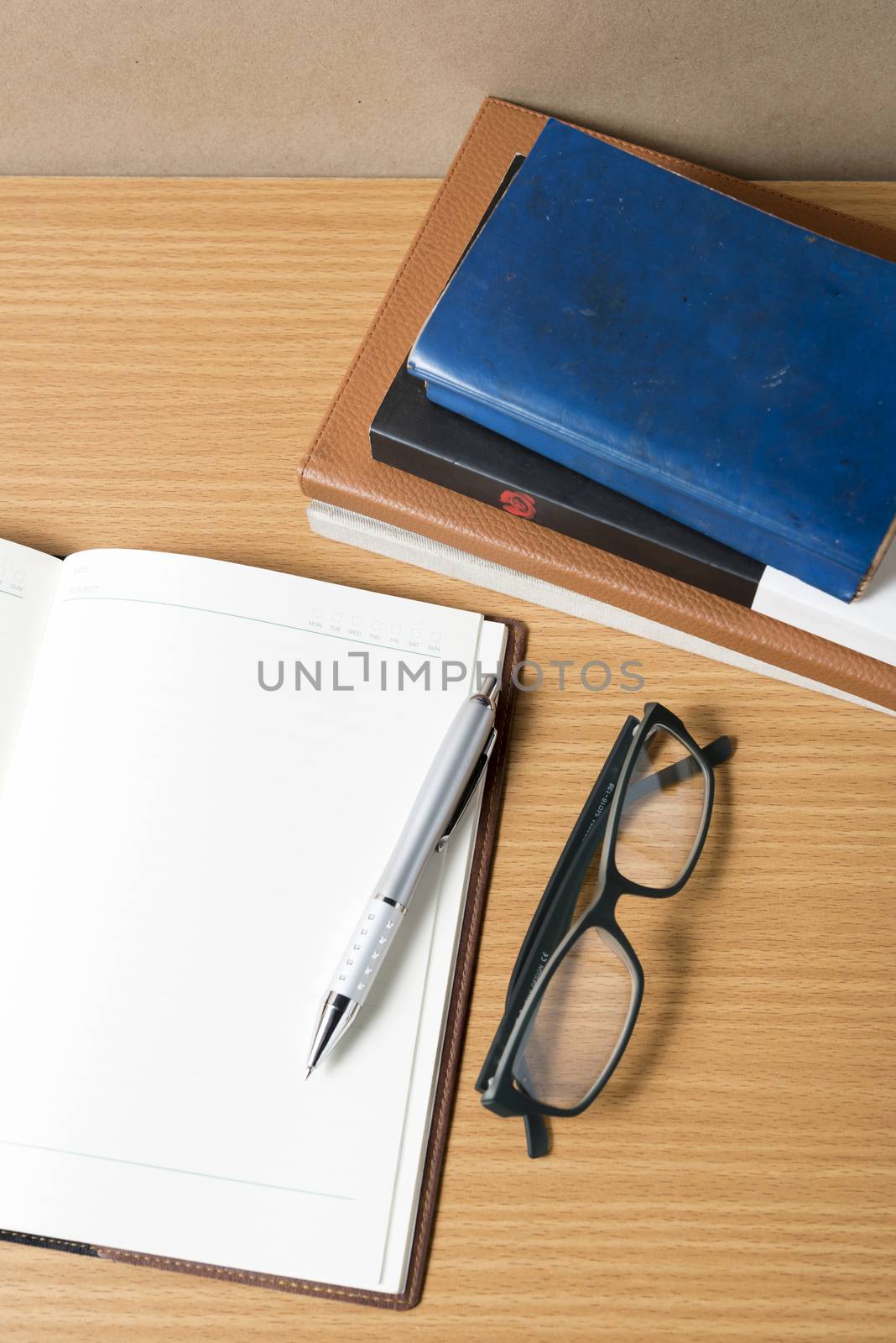 open notebook with stack of book on wood background