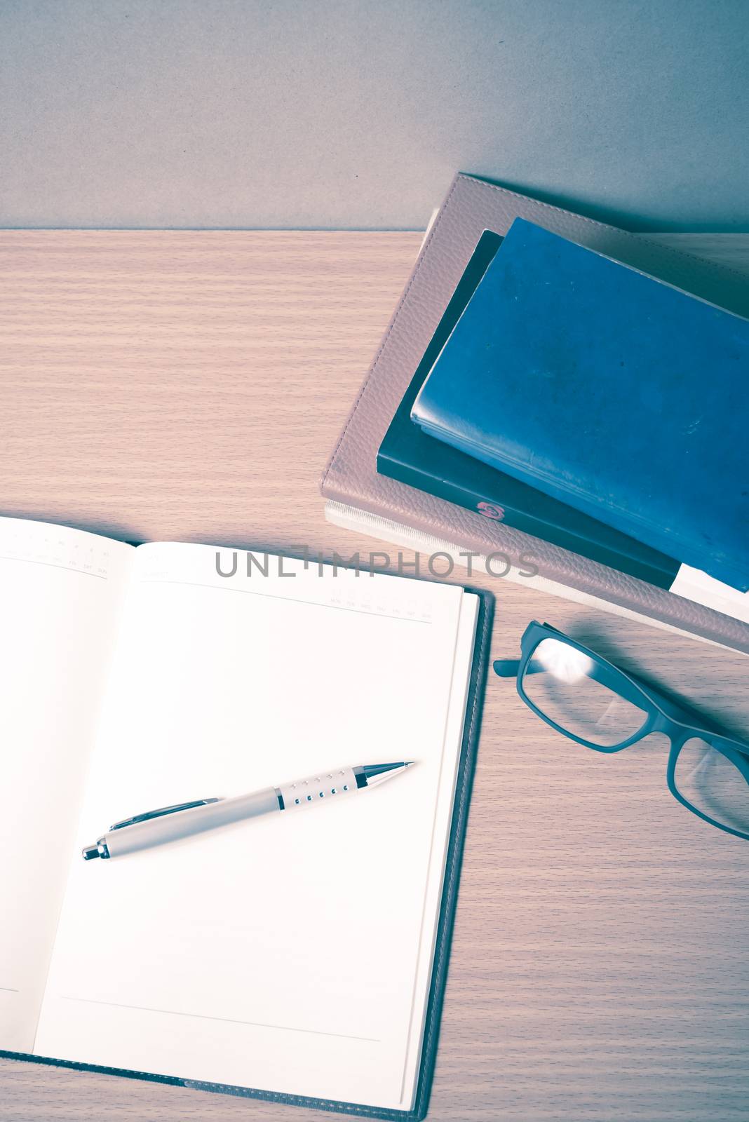 open notebook with stack of book on wood background vintage style