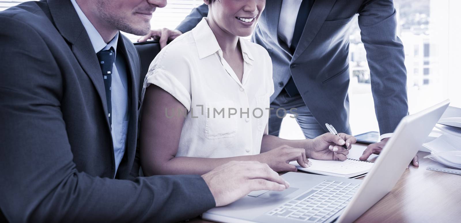 Smartly dressed young colleagues using laptop at office desk