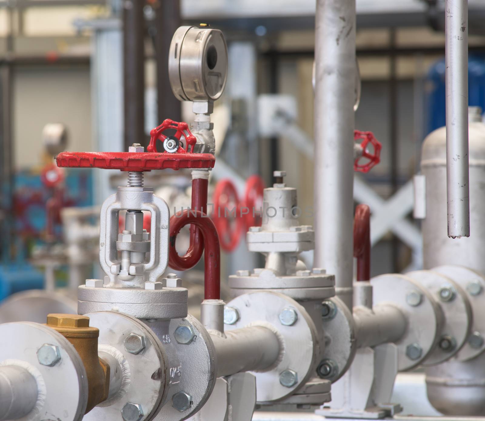 Pipes and valves in an industrial environment. Shallow depth of field with the nearest valve in focus.