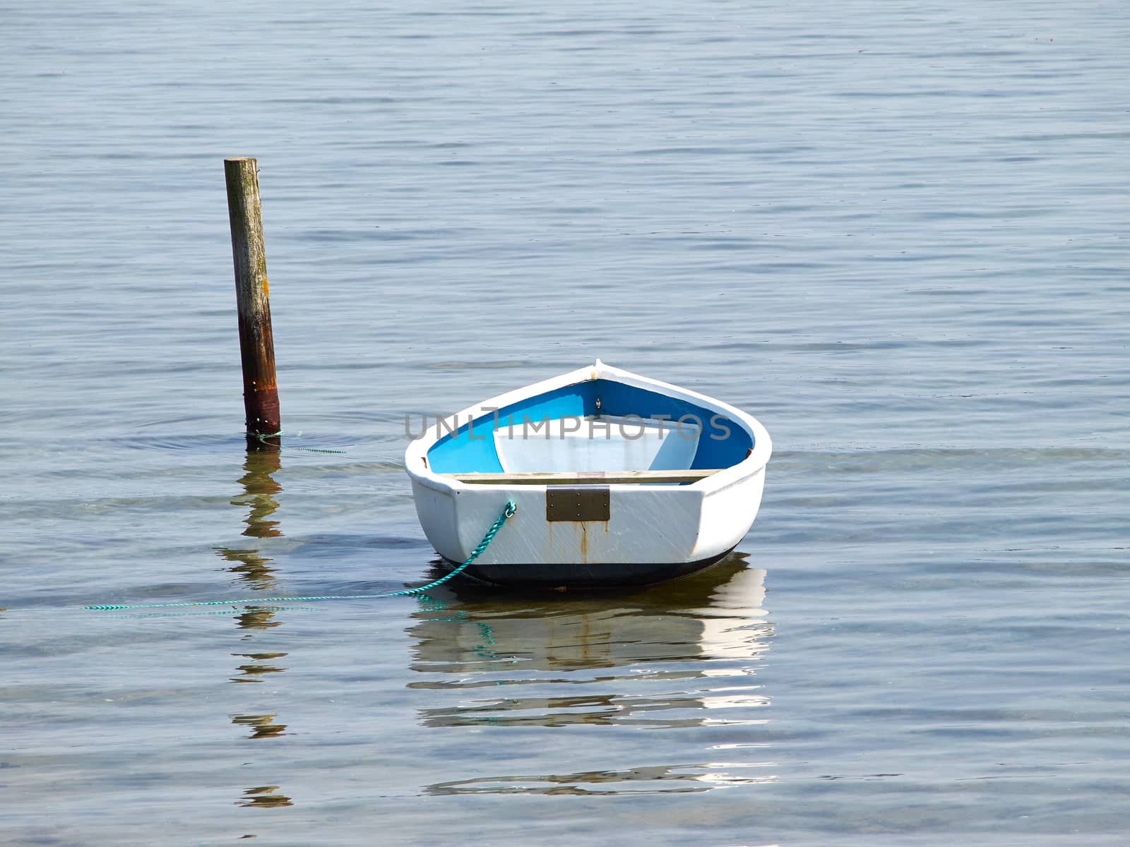 Moored small dingy rowing boat on still calm water  