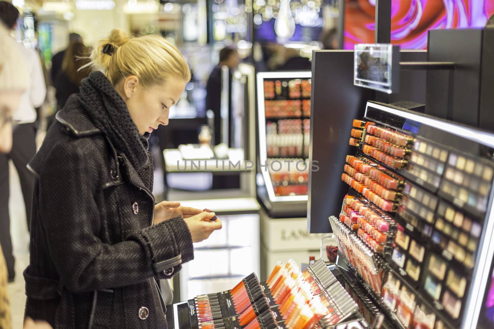 Beautiful blond lady testing  and buying cosmetics in a beauty store.